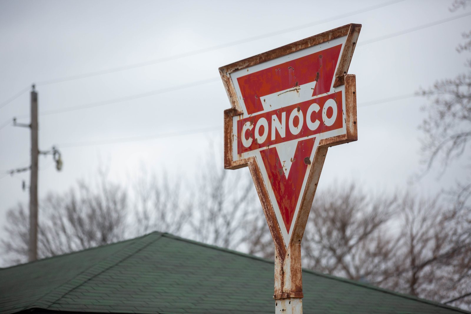 Weathered red Conoco sign against an overcast sky