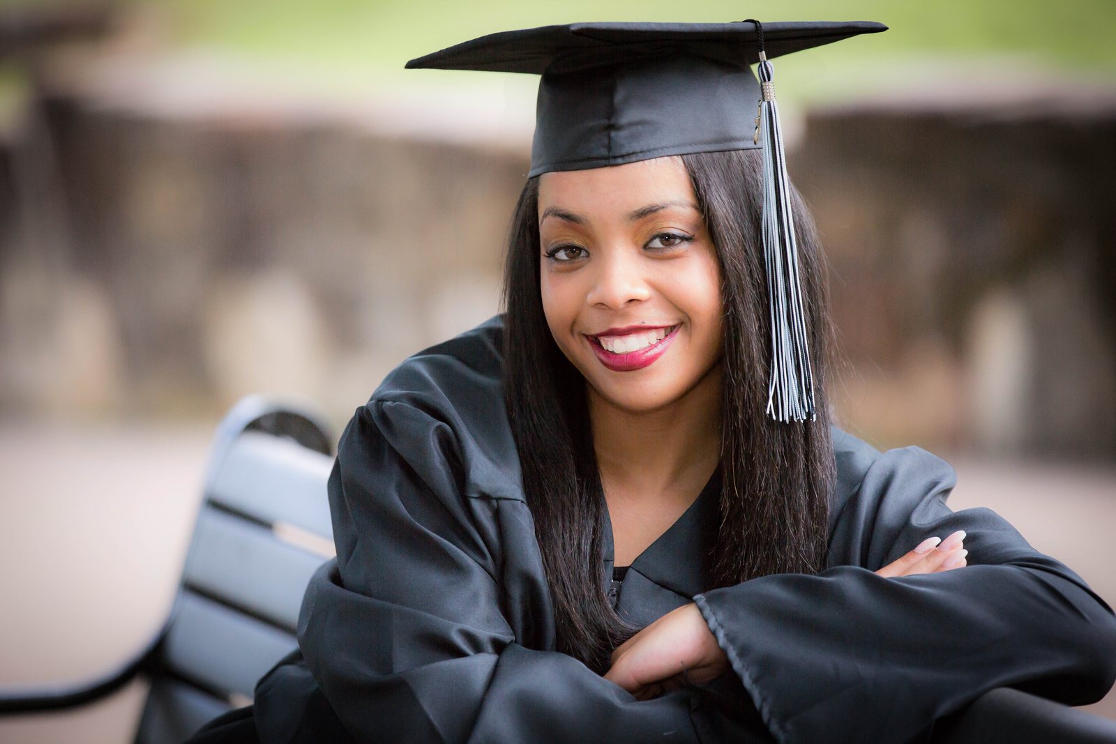 Graduate in cap and gown, arms folded, smiling at the camera