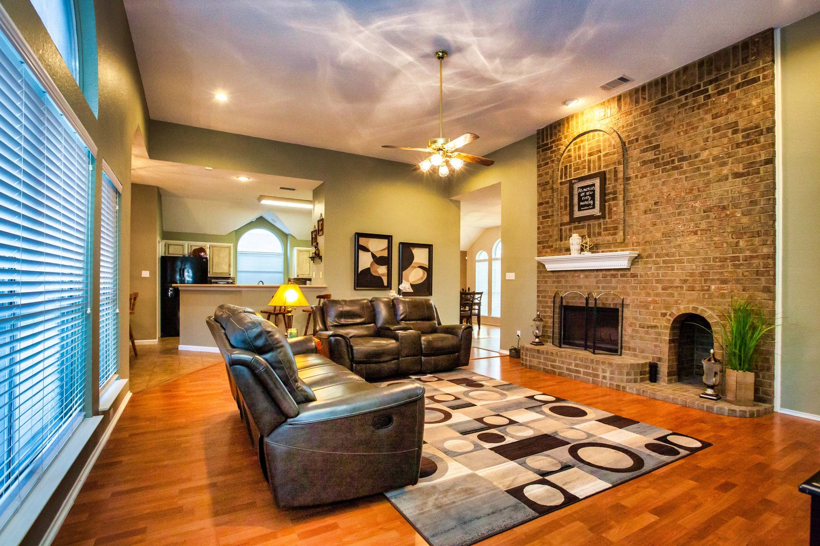 Living room with a brick fireplace, leather recliners, and a vaulted ceiling