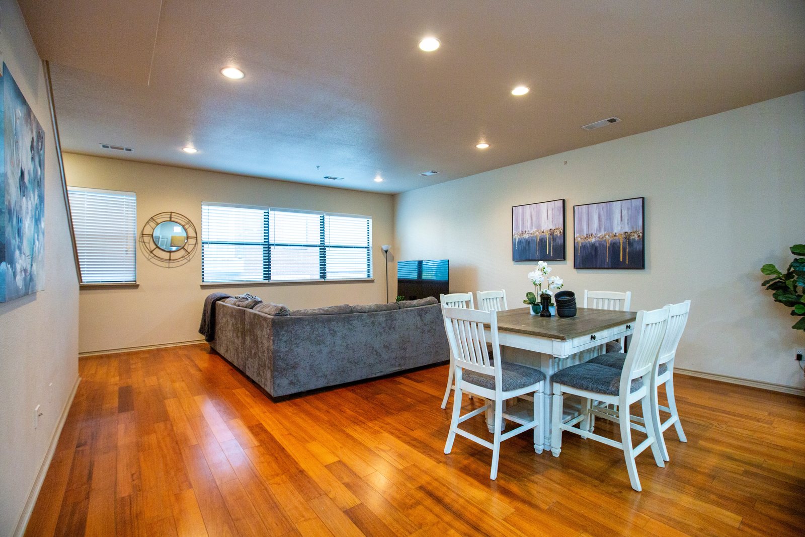Open living and dining room with hardwood floors and white chairs
