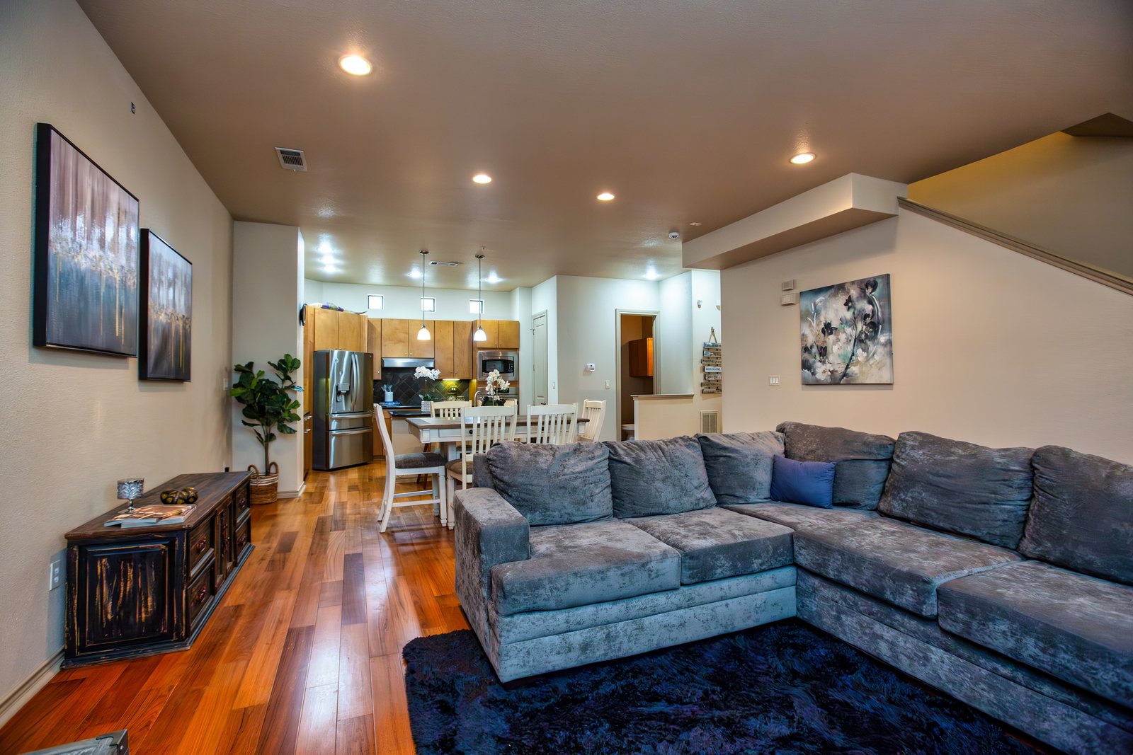 Blue sectional sofa in an open living room with a kitchen beyond